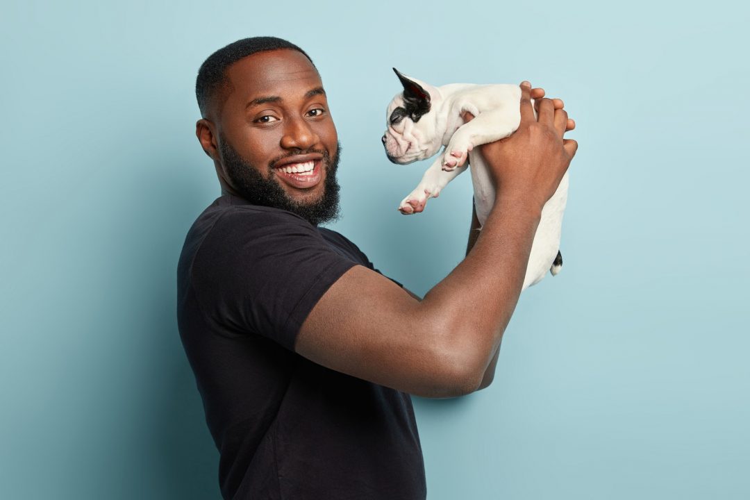A pleased black man finds a potential caretaker for his dog while he will be away, representing the concept of pet care.